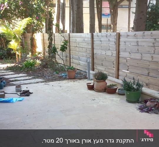 גדר עץ עם עציצים וציוד גינון בחצר
